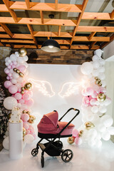 Pram or perambulator on a background arch decorated balloons, angel wings. Trendy cake with decor....