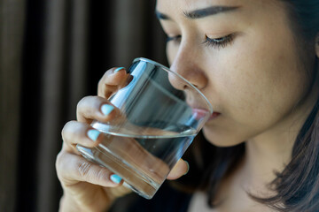 Asia young woman drinking fresh glass of water at home.