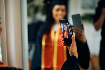 Close up of black female graduate takes selfie with cell phone.