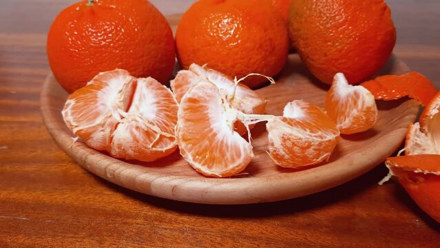 Slices of tangerine Murcott and whole fruits on wooden dish