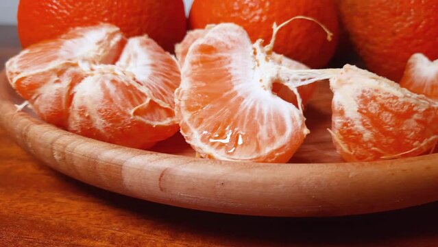 Slices of tangerine Murcott against whole fruits on wooden dish