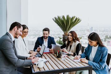 Group of hispanic business people in a informal meeting using laptop on the terrace of the office...