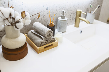 Fototapeta na wymiar luxury modern bathroom interior with gold tap (faucet), grey stone walls, hand towels and liquid soap. Scandinavian minimalistic style.