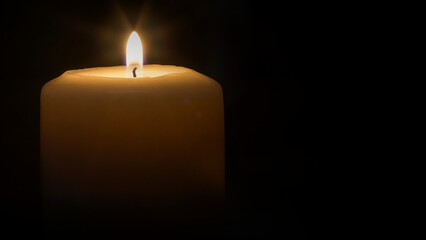 A lit candle with a black background.