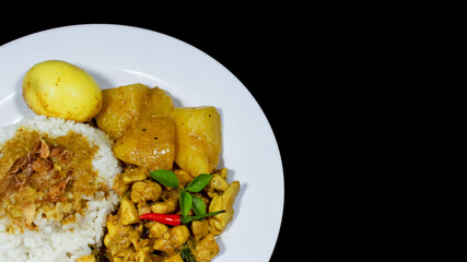 High Angle of Chicken curry rice in yellow spice sauce with potatoes and boiled egg served on white plate isolated on black dark background. Top view angle Chicken curry rice.