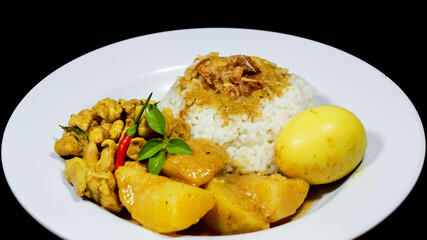 Side Angle of Chicken curry rice in yellow spice sauce with potatoes and boiled egg served on white plate isolated on black dark background