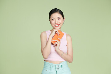 Thoughtful young happy asian woman smiling while holding mobile phone