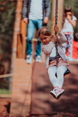 A little girl playing in the park. The concept of family socializing in the park. A girl swings on a swing, plays creative games