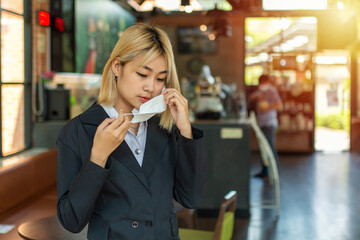 Close up portrait of beautiful business woman  and puts on protective mask on her face of in the cafe shop.