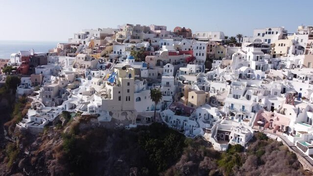 Aerial: Slow panning drone shot of Oia in Santorini, Greece during golden hour