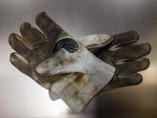 dirty work leather gloves over a metal sheet