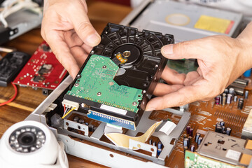 Technician remove a hard disk drive from the CCTV DVR recorder case, to install a new hard drive...