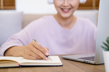 Close up hand - student wear wireless headphone study online with skype teacher, happy young woman...