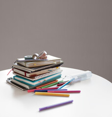 Diaries, notebooks, and colorful pens for scheduling are neatly placed on the indoor white table.
