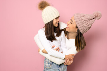 Funny smiling young woman and little kid girl sisters wearing casual t-shirts hugging looking each...