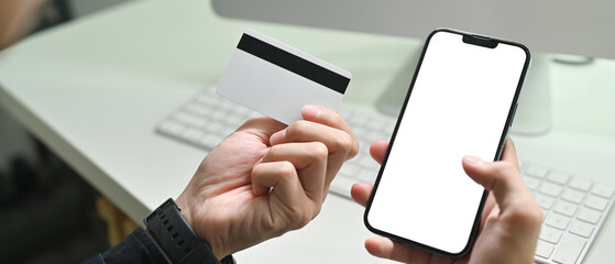 Close up view of man holding credit cad and using mobile phone smartphone for online banking transaction - obrazy, fototapety, plakaty