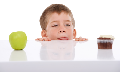 A boy faced with the decision to choose between a healthy apple and an unhealthy cupcake. He is seen craving junk food while looking at chocolate candy on the table isolated on a PNG background.