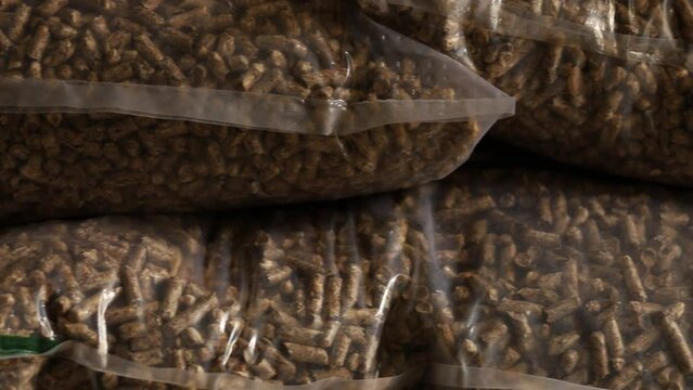 Slider shot of bags of wood pellets stacked on each other, for use as an eco-friendly renewable organic biofuel or mulch in the garden