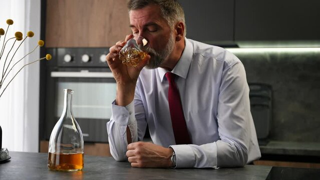 Tired Upset Mature Man In Elegant Suit Drinking Whiskey At Home, Sitting Alone.