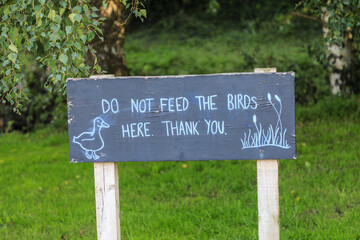 A sign saying 'do not feed the birds here thank you' England, UK
 - Powered by Adobe