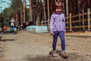 Fototapeta premium A little girl playing in the park. The concept of family socializing in the park. A girl swings on a swing, plays creative games