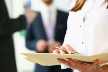 Women hands holding pen and documents in background business people