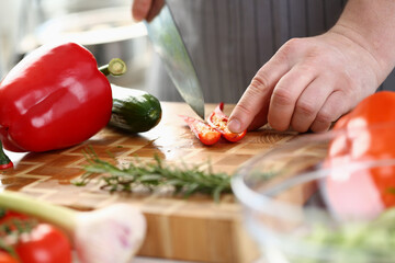 Chef cuts chili peppers on board closeup