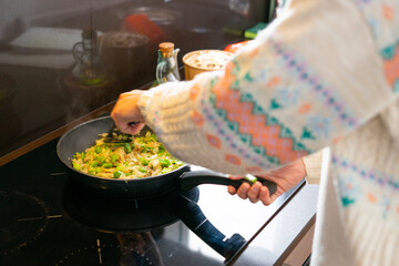 Girl cooking. Girl stirring vegetables in paella. Mushrooms, green and red peppers and onion	