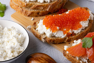 Sandwiches with red caviar, cottage cheese and salted salmon. Wooden cutting Board. Close up