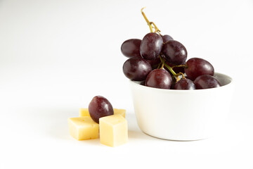 red grapes in a bowl with cheese on a white background