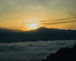 Golden surnise behind the Titiwangsa range mountains in Lenggong, Perak with sea clouds.