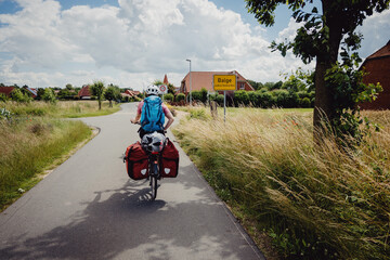 Frau auf einer Fahrradtour durch Niedersachsen passiert das Ortsschild von Balge, Deutschland