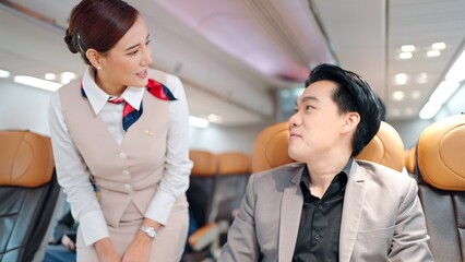 Flight captain or stewardess in air hostess uniform talking with passengers on airplane