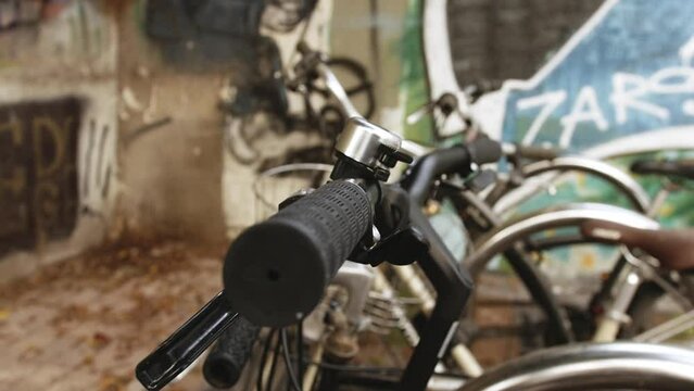 A close-up of a black bicycle's handlebars, with the grips, brakes, and frame all in sharp focus. Providing a dynamic view of the bike, the camera slowly pans from right to left. Bicycle on the street