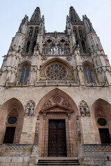 Fototapeta na wymiar Entrada principal de la catedral de Burgos con sus preciosas vidrieras y sus enormes campanarios visto desde abajo.