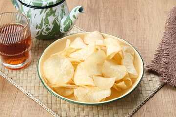 Keripik Singkong or Cassava Chips, Indonesian traditional snack. Served in bowl on wooden background.
