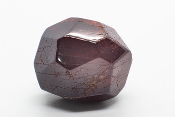 Dodecahedral natural deep red garnet lightly tumbled polished crystal isolated on a white surface background macro photography