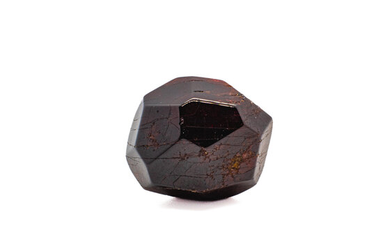 Dodecahedral natural deep red garnet lightly tumbled polished crystal isolated on a white surface background macro photography