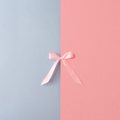 Pink ribbon bow on pink and blue pastel  background. Flat lay concept.