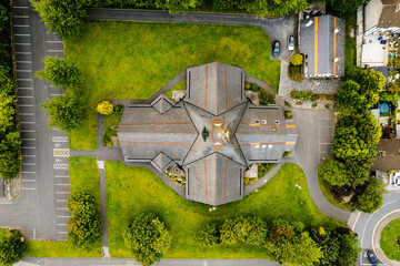 Aerial top down view on a church in a cross shape with green lawn and car park. City architecture.