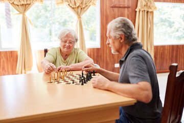 Couple of seniors playing chess together with concentration