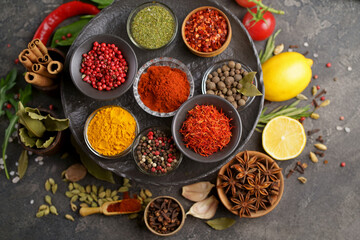 Set of spices and herbs. Indian food. Pepper, salt, paprika, basil, turmeric. On a black wooden board. View from above. Free copy space.