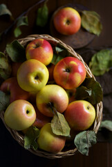 Ripe apples in a basket, with leaves around it