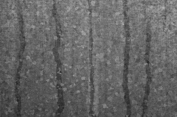 gray background, the photo shows a sheet of galvanized iron and traces of water on it