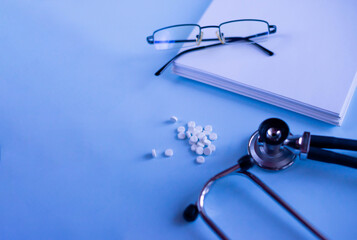 Doctor's set: a notebook for recording patient complaints, a fanendoscope, glasses and pills and vitamins. Medical background. Medical first aid kit and medicine concept.