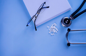 Doctor's set: a notebook for recording patient complaints, a fanendoscope, glasses and pills and vitamins. Medical background. Medical first aid kit and medicine concept.