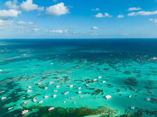 Fototapeta na wymiar Aerial panorama of many anchoring yachts and tourist boats in the turquoise Caribbean sea. Clear blue sky on the horizon. Best destination for vacation in Punta Cana
