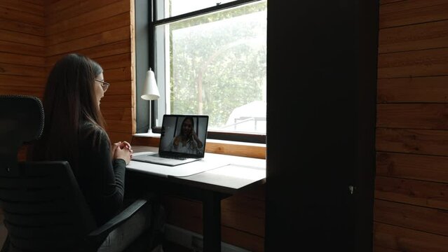 Remote work in a coworking space: Young business woman having an online meeting with her remote team