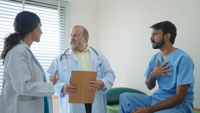 Professional woman doctor and asian senior male doctor talking and encourage an Indian male patient has been treated with doctor at the hospital