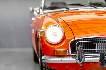 Fototapeta premium the shining front light of a red historic convertible